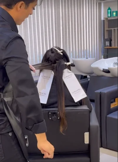 Mãos aplicando produto em uma mecha separada com papel