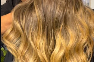 Cabelo loiro ondulado em movimento, com luz quente